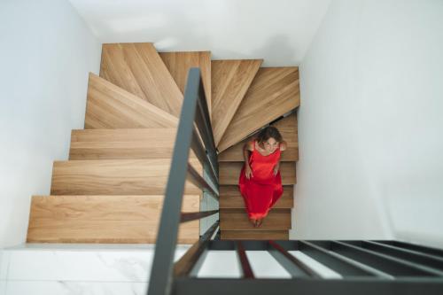 a woman in a red dress walking down the stairs at Karnayo apartments in Kavala