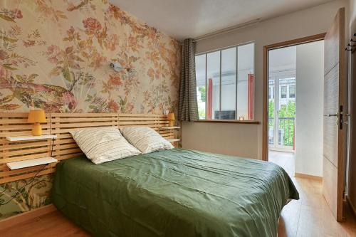 a bedroom with a bed with a green comforter at Oiseaux du Paradis in Amélie-les-Bains-Palalda