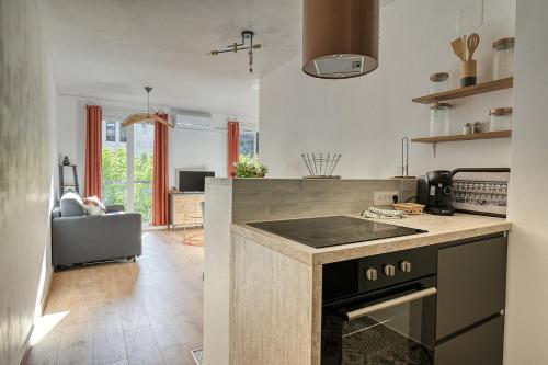 Il comprend une cuisine équipée d'une cuisinière. - un four supérieur à côté d'un salon dans l'établissement Oiseaux du Paradis, à Amélie-les-Bains-Palalda