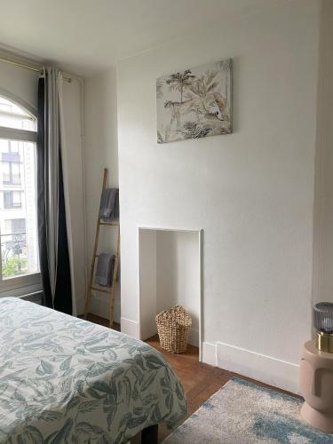 une chambre avec un lit et un tableau au mur dans l'établissement Appartement à 10 min du Stade de France, à Saint-Denis
