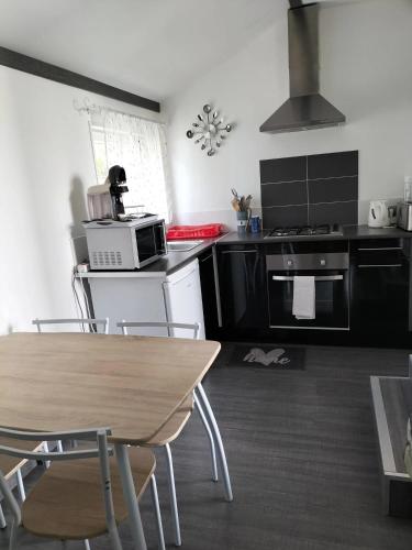 une cuisine avec des appareils en noir et blanc et une table dans l'établissement Studio charmant à Vierville-sur-Mer - 30m² avec jardin, à Vierville-sur-Mer