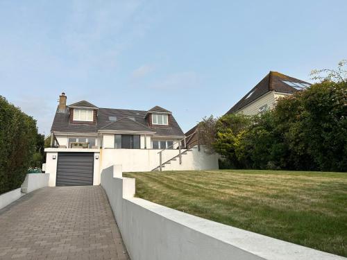 a house with a garage and a grass yard at Sanctuary by the Sea with large room incl lounge area, bathroom, direct garden access & free parking in Rottingdean