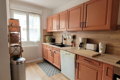 - une cuisine avec des placards en bois et un lave-vaisselle blanc dans l'établissement La petite maison rose au centre d'Albi, à Albi