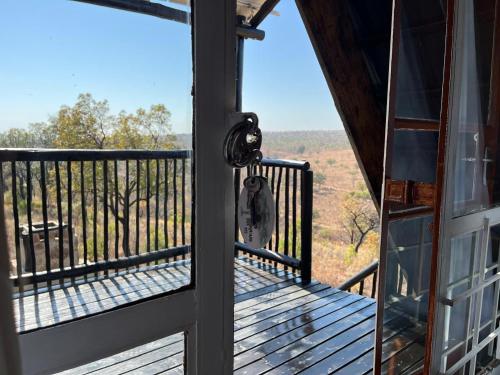 a door to a balcony with a view of the woods at Tonquani Bush Chalet in Rustenburg