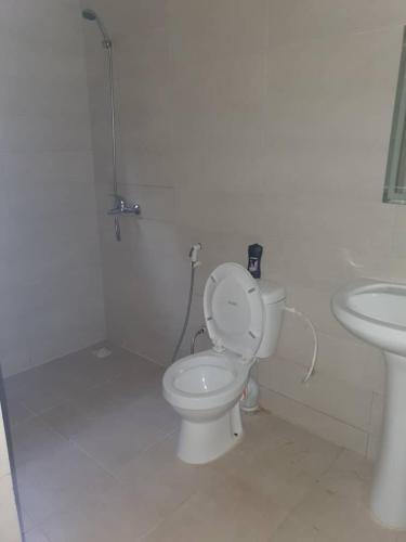 a white bathroom with a toilet and a sink at KJ Rooms in Sere Kunda