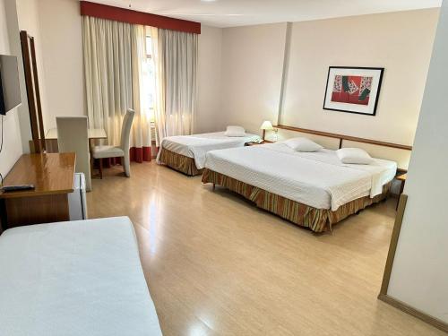 a hotel room with two beds and a table at César Park Hotel in Juiz de Fora