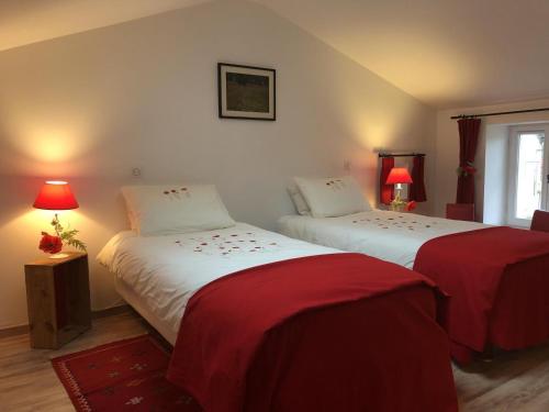 two beds in a room with red and white sheets at La biche in Bonnes