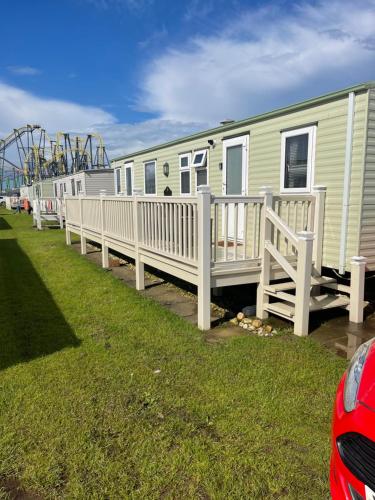 a row of mobile homes with a roller coaster at Blue 4 Caravan Ingoldmells 6 berth 3 bedrooms in Ingoldmells