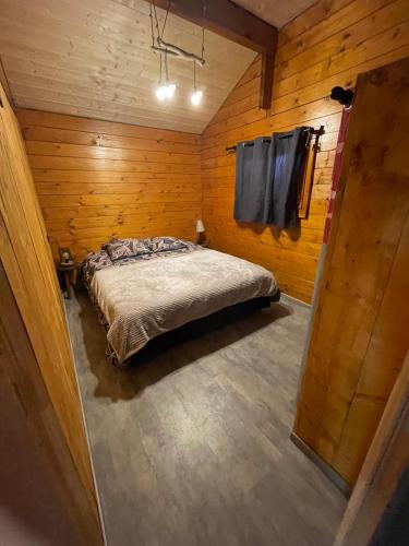 une chambre avec un lit dans une pièce en bois dans l'établissement Le petit chalet du mouralet, à Légna