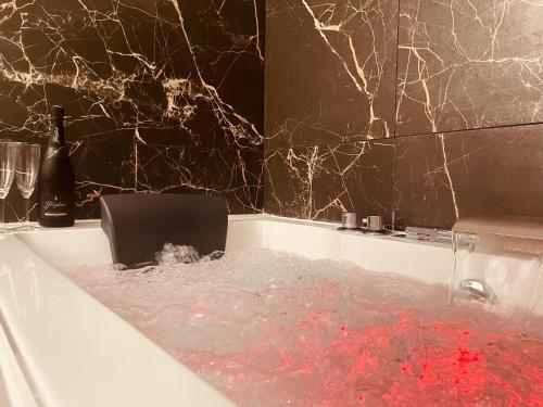 a bath tub filled with water with a bottle of wine at Appartement cosy et charme - 347 in Rouen