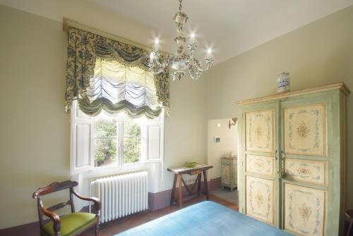 a room with a window and a chair and a chandelier at Villa Poggio Bello in Florence