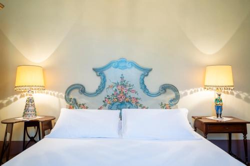 a bedroom with a white bed with two lamps at Villa Poggio Bello in Florence