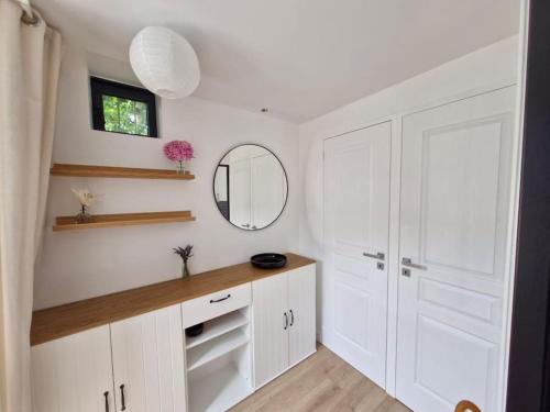 La salle de bains est pourvue de placards blancs et d'un miroir. dans l'établissement Maison de pêcheurs entièrement rénovée, à Saint-Pierre-en-Port