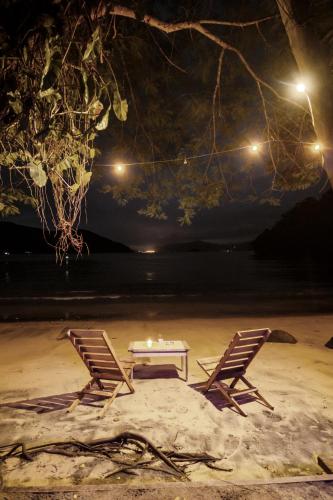 two chairs and a table on the beach at night at Bonito Paraiso Ilha Grande in Abraão