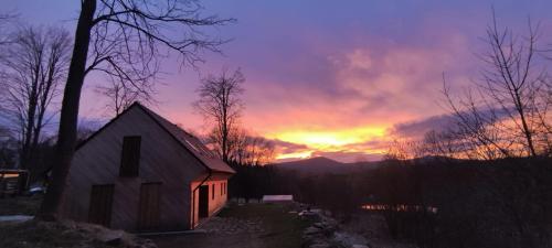 a sunset over a house with the sun setting in the background at Apartmán U Hvězdáře in Křišťanovice