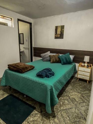 a bedroom with a bed with a green blanket at Casa San Bartolo in Antigua Guatemala