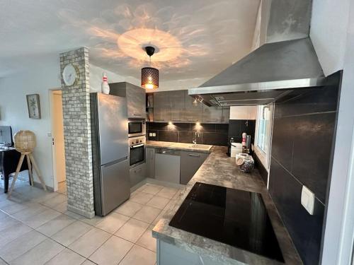 une grande cuisine avec des appareils en acier inoxydable et un plafond dans l'établissement L'appart Côté Sud, à Istres