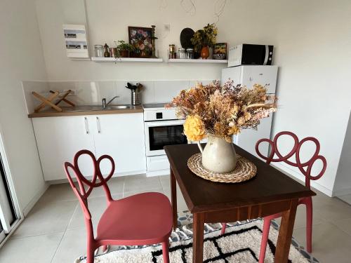 - une cuisine avec une table, des chaises et un vase fleuri dans l'établissement Maison 60 m plage, à Saint-Hilaire-de-Riez