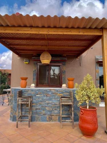a patio with two stools and a building with a porch at Auberge Kenza in Tahannout