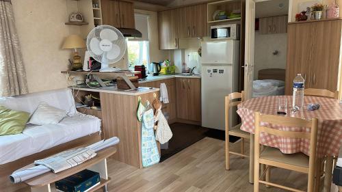Il comprend une petite cuisine avec une table et un réfrigérateur. dans l'établissement mobilhome, à Bretignolles-sur-Mer