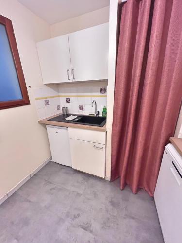 a small kitchen with a sink and a red curtain at Appartement le Terracotta - Parking - Place du Capitole in Toulouse