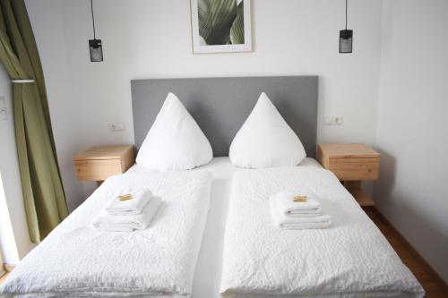 a bedroom with two beds with white sheets and towels at Hike Inn Hotels by Emmerich in Winningen