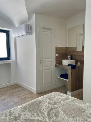 Cette chambre blanche comprend un lit et un lavabo. dans l'établissement Le Loft, à Sainte Anastasie - Aubarne