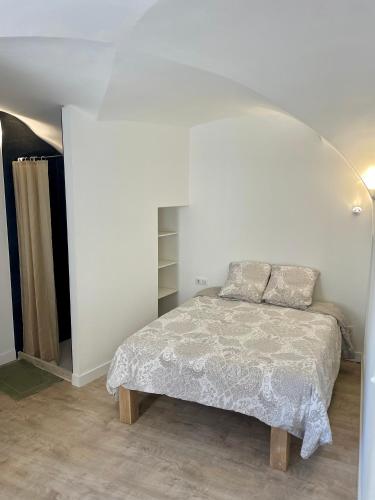 une chambre avec un lit et un mur blanc dans l'établissement Le Loft, à Sainte Anastasie - Aubarne