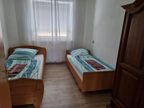 two beds in a small room with a window at Ferienwohnung 2 mit 3 Schlafzimmer und Garten in Crailsheim