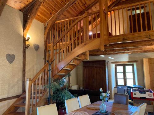 a wooden staircase in a living room with a table at Domaine Au Vert Gna ! in Saint-Hostien