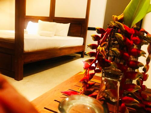 a room with a bed and a table with a vase at Chamara Inn in Talpe