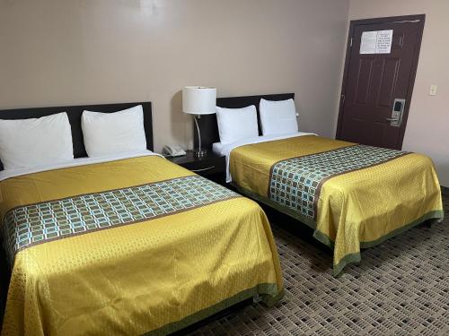 two beds with yellow sheets in a hotel room at Economy Inn & Suites in Ashtabula