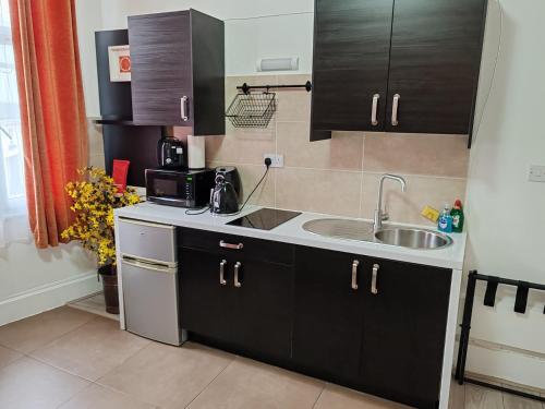 a small kitchen with a sink and a microwave at Kilburn High Road Studio apartments in London
