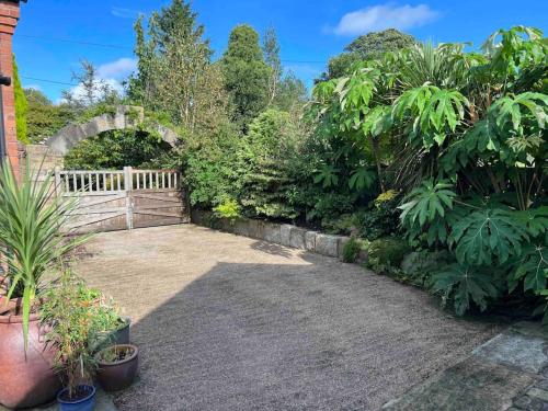 a garden with a wooden gate and some plants at The Chapel - A Hidden Gem with Private Pool & Bar in Stone
