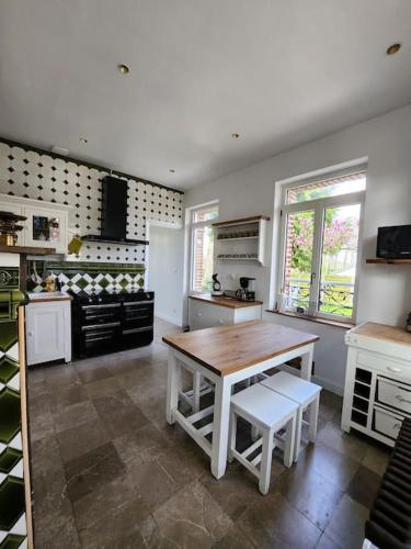 une cuisine avec une table en bois et des appareils électroménagers blancs dans l'établissement Manoir aux roses, gîte 15 personnes avec Spa, à Bonningues-lès-Ardres