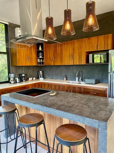 a kitchen with a counter with stools and a sink at Luxury Jungle Penthouse with Private Rooftop Pool in Chemuyil