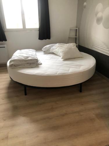 a large bed in a room with a wooden floor at La maison des amoureux in Tavant