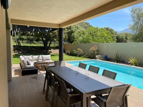 un patio avec une table et des chaises à côté d'une piscine dans l'établissement Casa olival, à Oletta