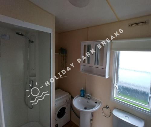 a small bathroom with a shower and a sink at Driftwood - Bronze 3 bedroom West Sands Sleeps 8 in Selsey