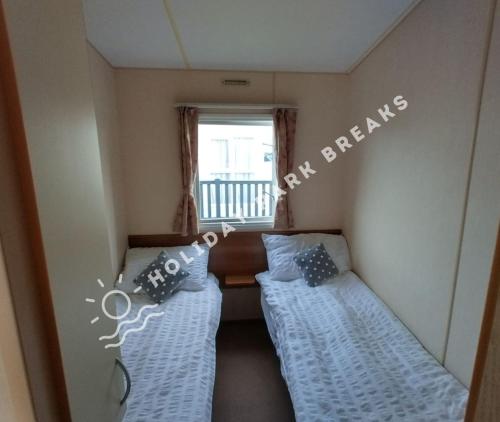 two beds in a small room with a window at Driftwood - Bronze 3 bedroom West Sands Sleeps 8 in Selsey