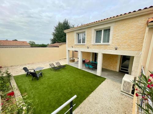a backyard with a lawn with chairs and a house at Gîte Ô Pallinois Proche du Futuroscope de Poitiers in Boussais