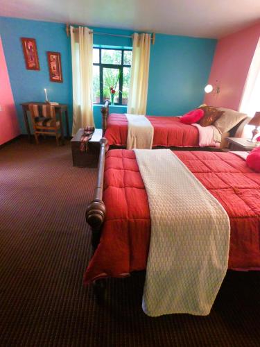 two beds in a room with blue and red walls at Casa Jazmín Hospedaje Familiar Eco Amigable - Huayoccari, Sacred Valley in Huayoccare