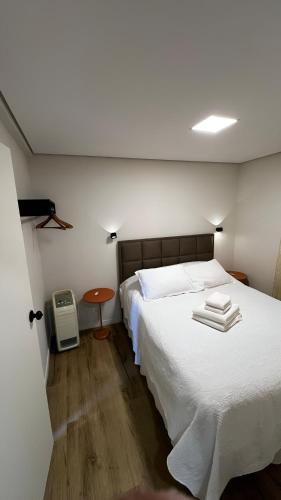 a bedroom with a large white bed and a table at Casa com Conforto, Tranquilidade em Meio à Natureza in Gonçalves