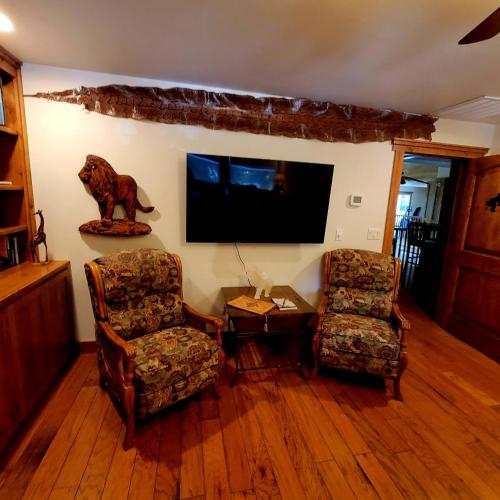 a living room with two chairs and a flat screen tv at Kings River Reflections in Sanger