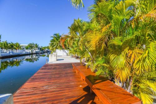 a wooden dock with palm trees and water at Cedar Cottage in Big Pine Key