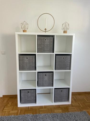 a white book shelf with baskets on it at Ferienwohnung Stadtnah im grünen in Ravensburg