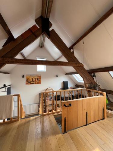 a large room with wooden floors and ceilings with wooden beams at Appartement 'Droom in de polder de Suite met prive sauna in Arnemuiden