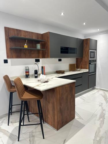 a kitchen with a wooden island with two chairs at Baie d'Alger in Husseïn Dey