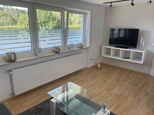 a living room with a tv and a glass table at Ferienwohnung Stadtnah im grünen in Ravensburg