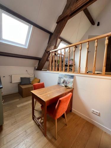 a dining room with a wooden table and a staircase at Appartement 'Droom in de polder de Suite met prive sauna in Arnemuiden